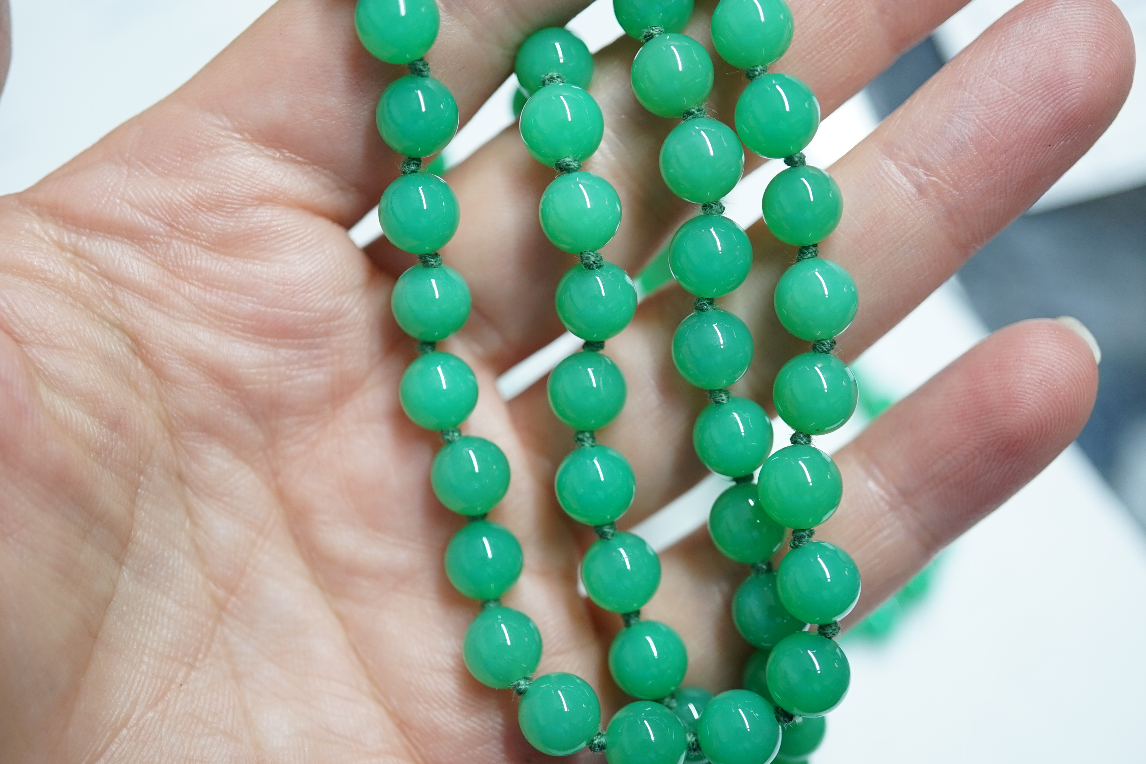 A modern long single strand jadeite bead necklace, with a cabochon jade and diamond chip cluster set 18k clasp